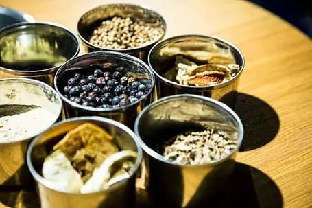 L'art et la science du gin : De quoi est fait le gin ? 1 Un groupe de boîtes métalliques remplies d'épices diverses, dont les ingrédients essentiels utilisés dans la production de gin.