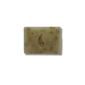Handcrafted soap bar with a textured crescent moon design and speckles, shown against a dark backdrop.